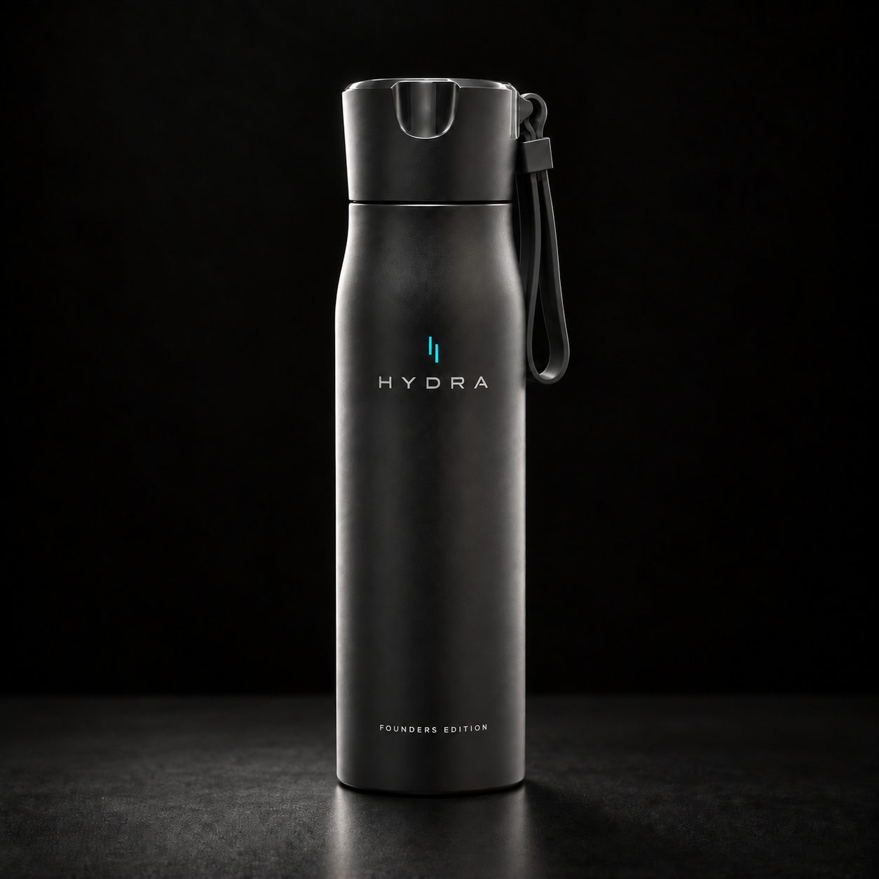 A matte black Hydra water bottle with a matching black flip-top lid and carrying loop, standing upright on a dark surface against a black background. The bottle features the HYDRA logo in white and a small blue accent, with 'FOUNDATION EDITION' printed near the bottom.